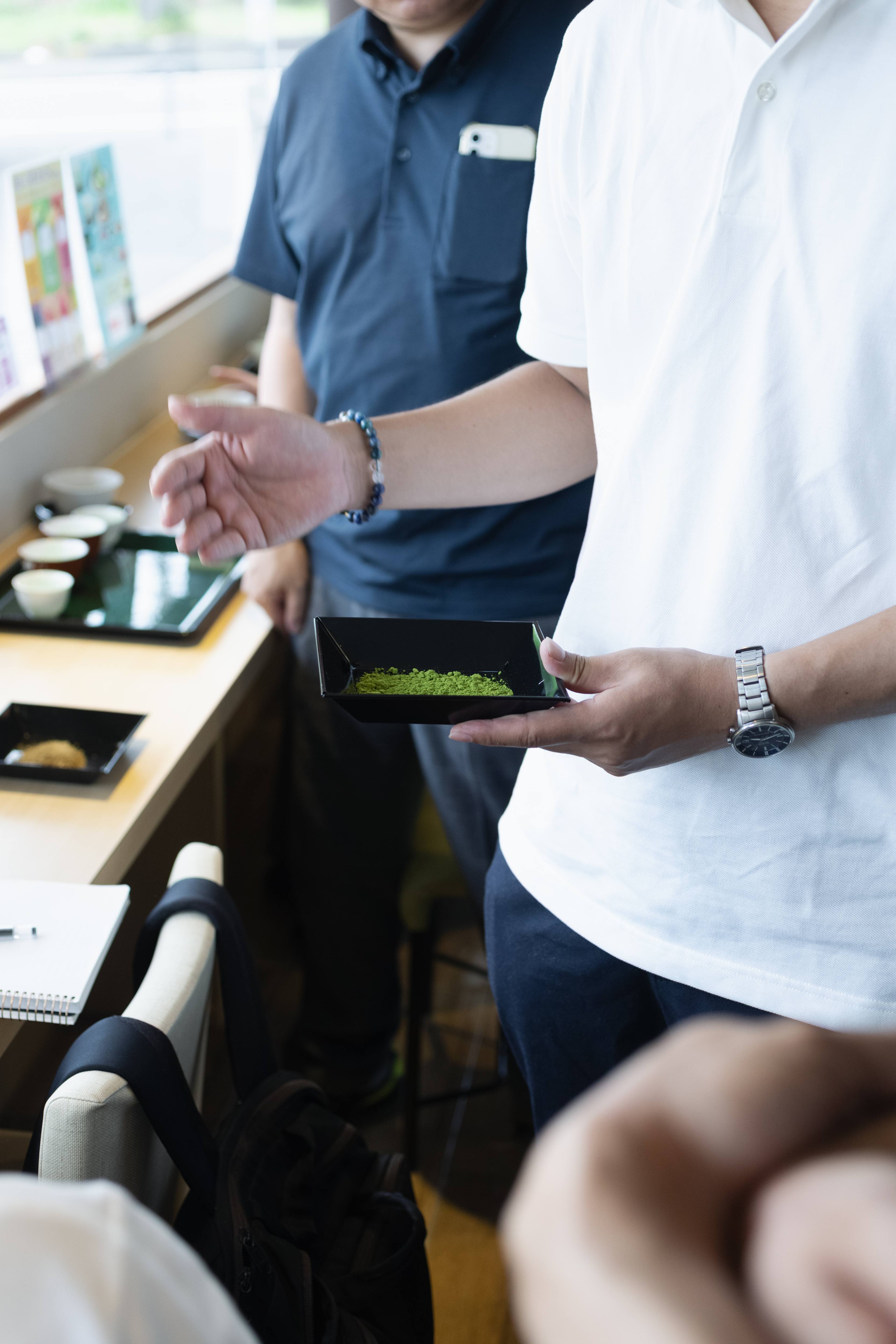 抹茶を手に来客へ説明する祥港園のスタッフ